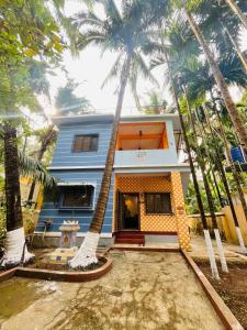 a blue house with palm trees in front of it at Sukrut Villa, Alibag in Thāl
