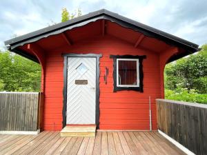 a red shed with a white door on a deck at 5 person holiday home in ULRIKA in Rimforsa