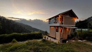 a small house on a hill with the sunset in the background at Nirvana Trueliving in Nagar