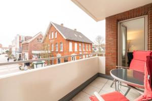 a balcony with red chairs and a glass table at Ferienwohnung Bäumer Borkum - Nichtraucher & allergikerfreundlich in Borkum