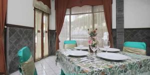 a dining room table with a table cloth and green chairs at Hotel Lestari Near Lippo Plaza Mall Jember in Jember