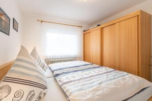a bedroom with a bed and a wooden cabinet at Ferienwohnung Bäumer Borkum - Nichtraucher & allergikerfreundlich in Borkum