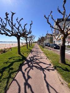 a sidewalk with trees on the side of a beach at Ti Mad, Echappée belle à La Baule - mer et piscine in Guérande