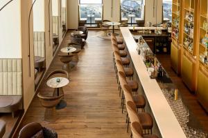 a restaurant with a long bar with chairs and tables at The Cloud One Wien-Staatsoper in Vienna +83 photos