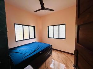 a bedroom with a blue bed and two windows at Sukrut Villa, Alibag in Thāl