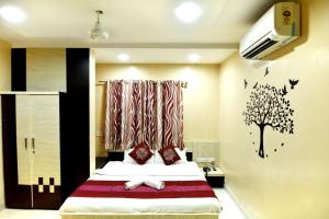a bedroom with a bed with a tree decal on the wall at Hotel Gulmohar in Indore