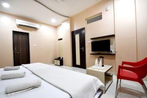 a hotel room with a bed and a red chair at Hotel Gulmohar in Indore