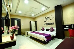 a bedroom with a bed and a desk and flowers at Hotel Gulmohar in Indore