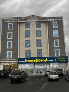 a large building with cars parked in a parking lot at شقق وجهة الوصول in Ar Rawshān