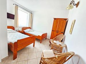 a bedroom with two beds and a chair and a window at Willa Linc Łeba in Łeba