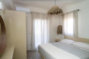 a white bedroom with a bed and a window at Small Cyclades Houses in Koufonisia