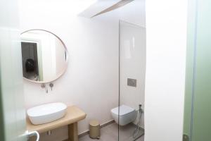 a white bathroom with a mirror and a toilet at Small Cyclades Houses in Koufonisia +7 photos