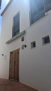 a white building with a wooden door and windows at Ruralis Las Nogalas in Montánchez