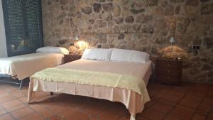 a bedroom with two beds and a stone wall at Ruralis Las Nogalas in Montánchez