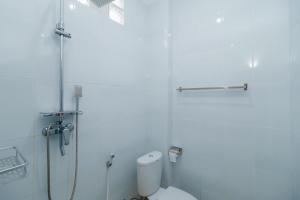 a white bathroom with a toilet and a shower at RedDoorz @ Kisaran Kota in Kisaran