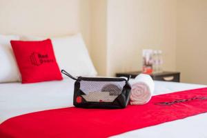 a black bag on a bed with a red blanket at RedDoorz @ Kisaran Kota in Kisaran