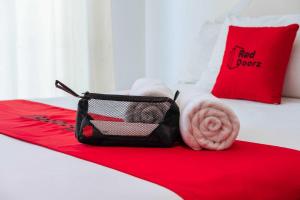a hotel room with a red bed with a red towel and a bag at RedDoorz @ Kisaran Kota in Kisaran +2 photos