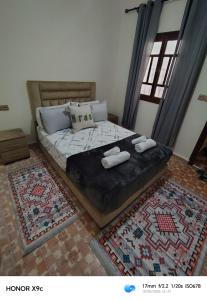ein Schlafzimmer mit einem Bett, zwei Kissen und zwei Teppichen in der Unterkunft PalmRest in Marrakesch