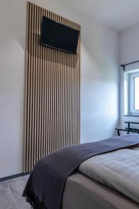 a bedroom with a bed with a flat screen tv on the wall at Asweiler Landliebe - klimatisierte Premiumfewo mit Balkon und Fernblick in Freisen