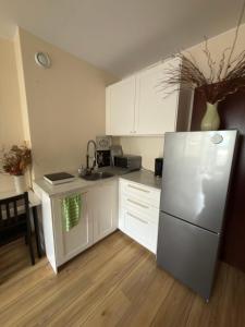 a kitchen with white cabinets and a stainless steel refrigerator at Apartament przy Koniu Trojańskim in Luboń