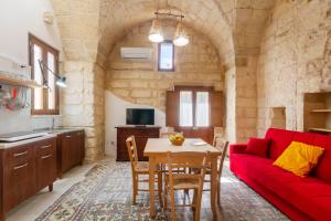a living room with a red couch and a table at GuestHost - La Pizzica Apartment in Cannole +9 photos