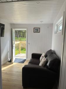 a black leather couch in a living room with a door at Corriemuckloch Unique Huts in Dunkeld