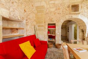 a red couch in a room with a stone wall at GuestHost - La Pizzica Apartment in Cannole