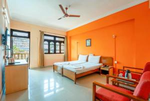 a bedroom with orange walls and a bed and a couch at Vasco Residency in Vasco Da Gama +22 photos