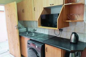 a kitchen with a sink and a washing machine at Budget Stays at Olivia Pines Guesthouse in Krugersdorp
