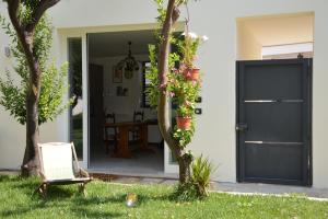 ein Haus mit einer schwarzen Tür und einem Stuhl im Gras in der Unterkunft Percebes Exclusive B&B in Cutrofiano