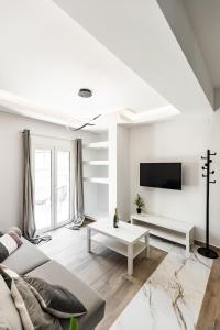 a white living room with a couch and a tv at Exclusive suite in Hersonissos