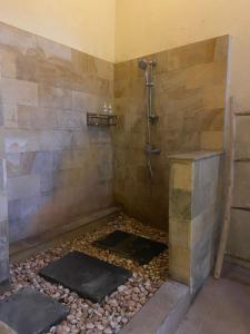 a bathroom with a shower and a pebble floor at Okawati Boutique Bungalows in Ubud +12 photos