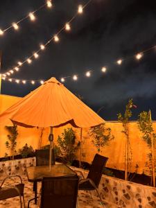 a table with an umbrella and chairs under lights at كوخ الجنة in Abha