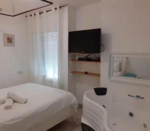 a white room with a bed and a tv at אצל דניאל במושבה - 2 צימרים מושלמים עם נוף לכינרת in Kinneret +6 photos