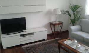 una sala de estar con TV en un centro de entretenimiento blanco en La Finestra Sul Mare, en Trieste