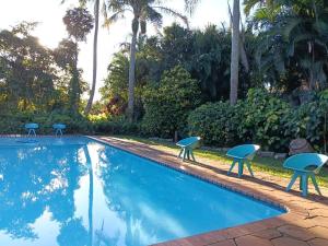 a swimming pool with three chairs next to it at Ocean House in St Lucia