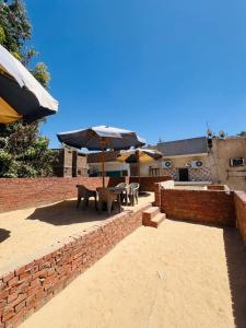 a patio with tables and umbrellas on a brick wall at Dara guest House in Aswan