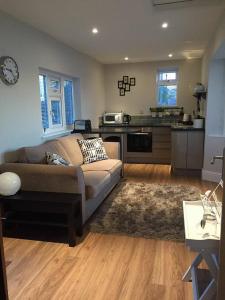 a living room with a couch and a kitchen at Copper's Cottage in Sheringham