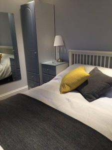 a bedroom with a bed with a yellow pillow and a mirror at Copper's Cottage in Sheringham