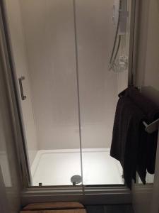 a shower with a glass door in a bathroom at Copper's Cottage in Sheringham