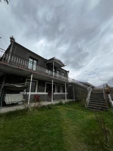 a building with a staircase and a grass yard at Maia's Guest House Gergeti in Kazbegi