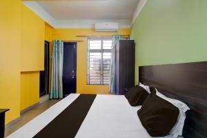 a bedroom with a bed with yellow walls and a window at Super Hotel O Sankaradeva Kalakshetra Formerly HK Residency in Dispur