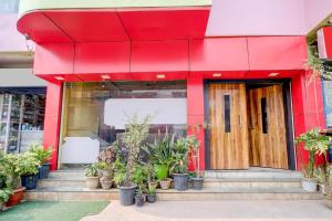 a red building with potted plants in front of it at Super Hotel O Sankaradeva Kalakshetra Formerly HK Residency in Dispur +35 photos