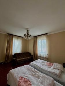 a bedroom with two beds and a couch and a chandelier at Maia's Guest House Gergeti in Kazbegi +12 photos