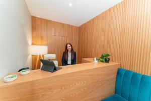 a woman standing behind a desk with a laptop at A&S Suítes Coimbra in Coimbra
