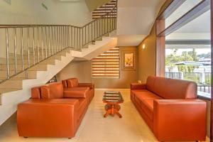 a living room with two leather couches and a staircase at Super Collection O RTO Office Uzhavoor Formerly Hotel Zodiac in Puduveli