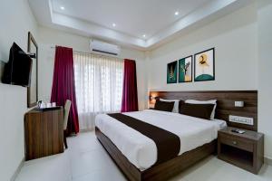 a bedroom with a large bed with red curtains at Super Collection O RTO Office Uzhavoor Formerly Hotel Zodiac in Puduveli +32 photos