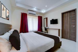 a bedroom with a large bed with red curtains at Super Collection O RTO Office Uzhavoor Formerly Hotel Zodiac in Puduveli