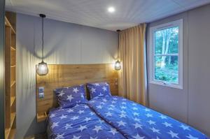 a bedroom with a bed with blue sheets and a window at Siblu Duinzicht in Koudekerke +33 photos