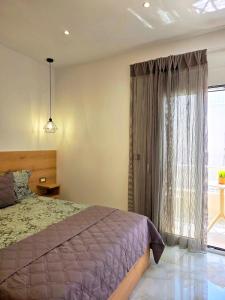 a bedroom with a bed and a large window at Anthouli homes 4, steps from beach and centre in Kardamaina